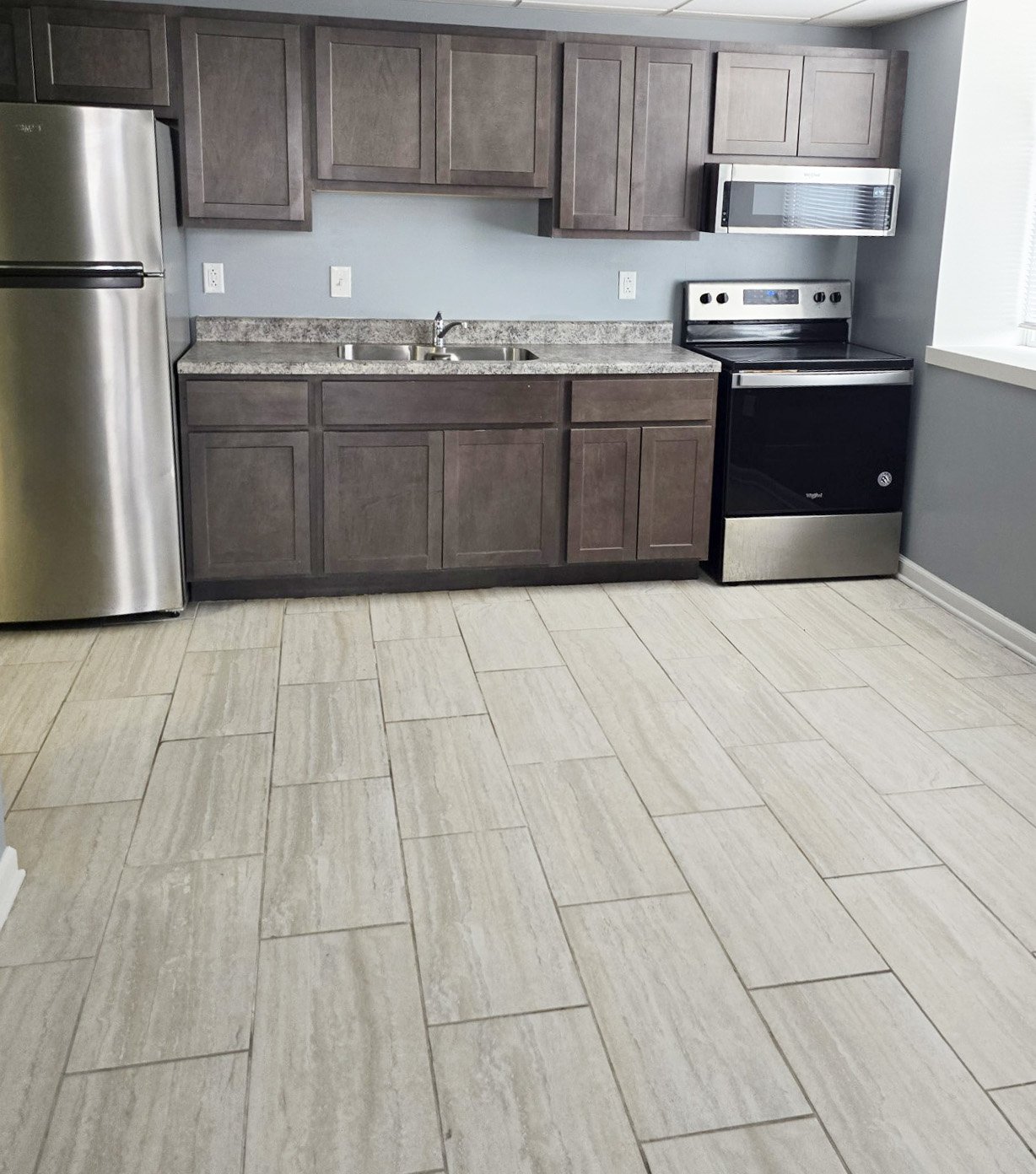 A kitchen with a refrigerator, sink, and oven.